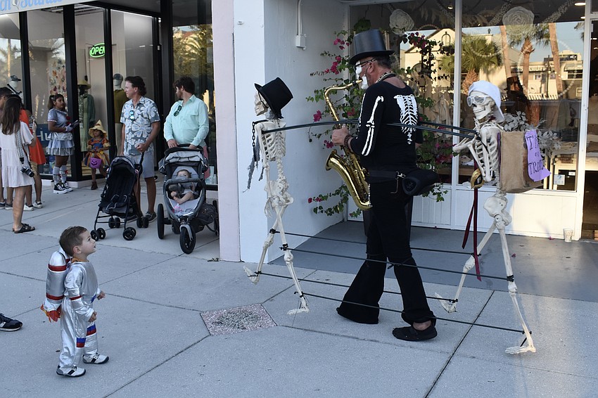 Jett Ginand, 1, encounters Boris and Sax as he makes his way down the sidewalk, accompanied by two walking skeletons.