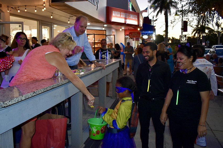 Brian and Cam Maddox hand out candy to Eliza Narain, 6, as her parents Kevan and Gaby Narain look on.