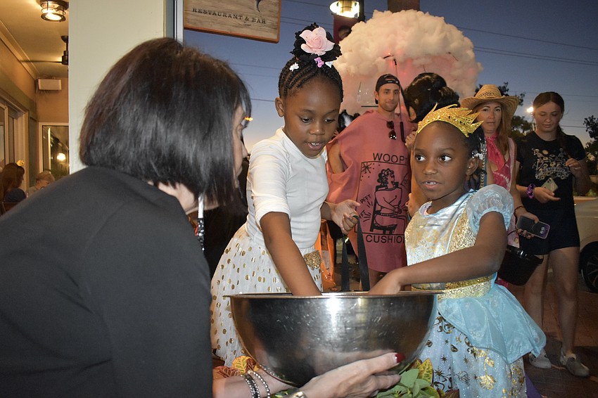 Alexis Skasko holds out a bowl of candy for Jeniah June, 9, and Arstasia June, 8.