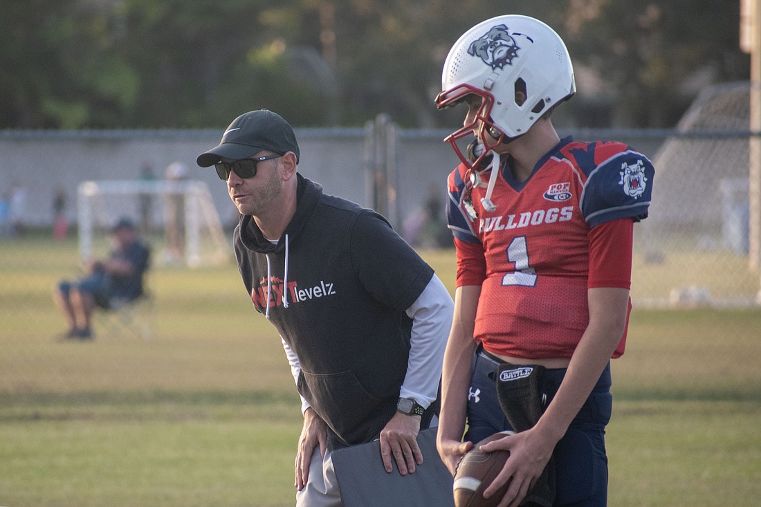 James Abelson, the East Manatee Bulldogs offensive coordinator, works with quarterback Nick Monserez at a Nov. 1 practice. Monserez will play for Cardinal Mooney High next season.