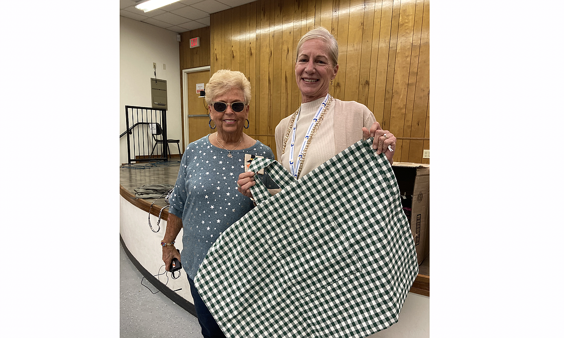 Barbara Hall, president of Memory Makers Quilt Guild, presents duffle bags to Sarah Carrigan of Guardian Ad Litem. Photo courtesy of Memory Makers Quilt Guild