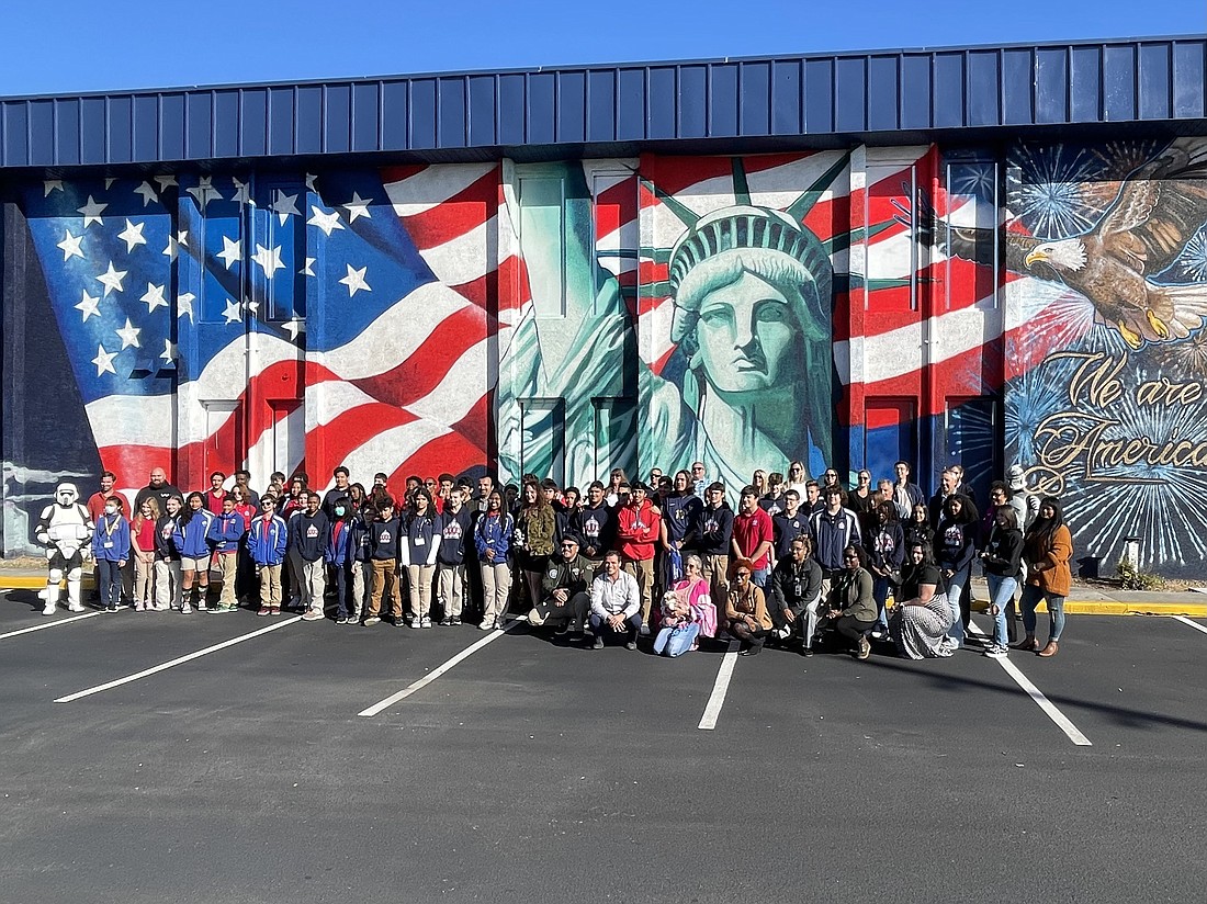 River City Science Academy students, officials and others stand in front of the 300-foot mural at the school at 7565 Beach Blvd. Artist Mary Joan Hison used 1,000 cans of spray paint to create the mural.