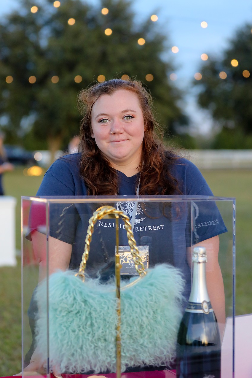 Volunteer Sarah Cripe poses with some of the live auction items.