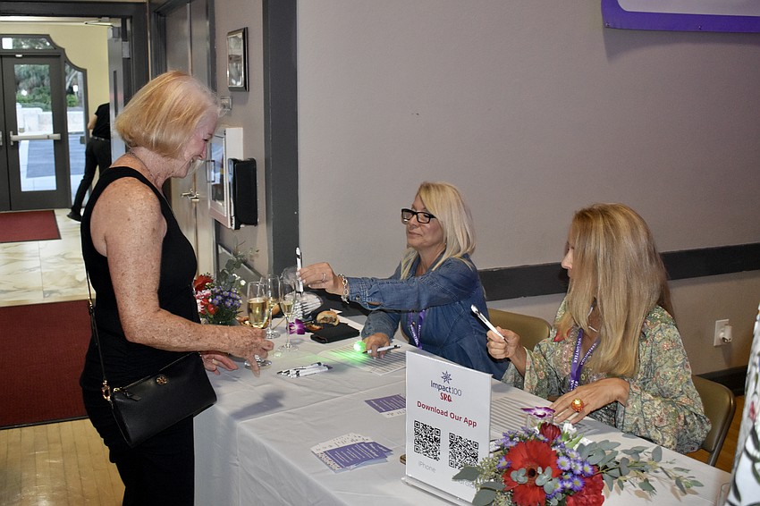 Sheril Miller signs in at a desk staffed by Stella Lappin and Cathy Sellers.
