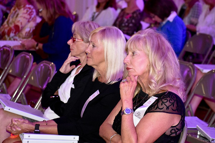 Cate Douglas, Bonnie Granatir and Impact100 SRQ board of directors members Judy Greenhill watch a presentation.