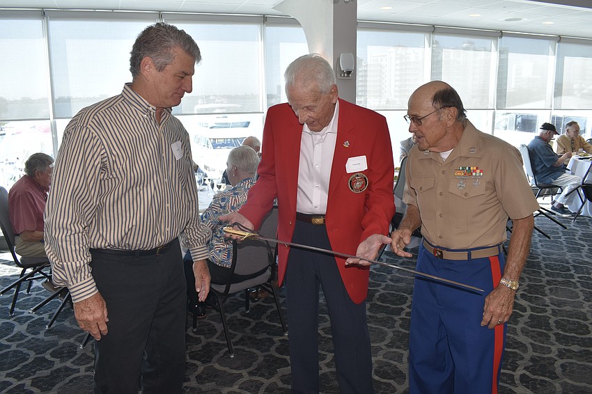 Mark Davis brings the sword for cutting the cake, which Frank Doyle and Tom Smith look over.