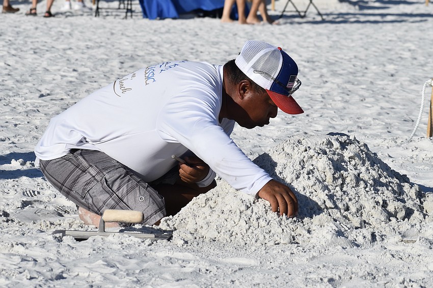 Kumpa Tawornprom from Safety Harbor, Florida, blows on the sculpture he is creating.
