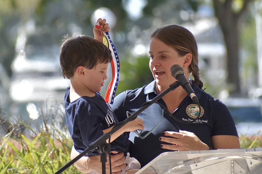 Graham Melton, 3, accompanies his mother Rep. Fiona McFarland, John H. McLain Woman Veteran of the Year, as she delivers a speech.
