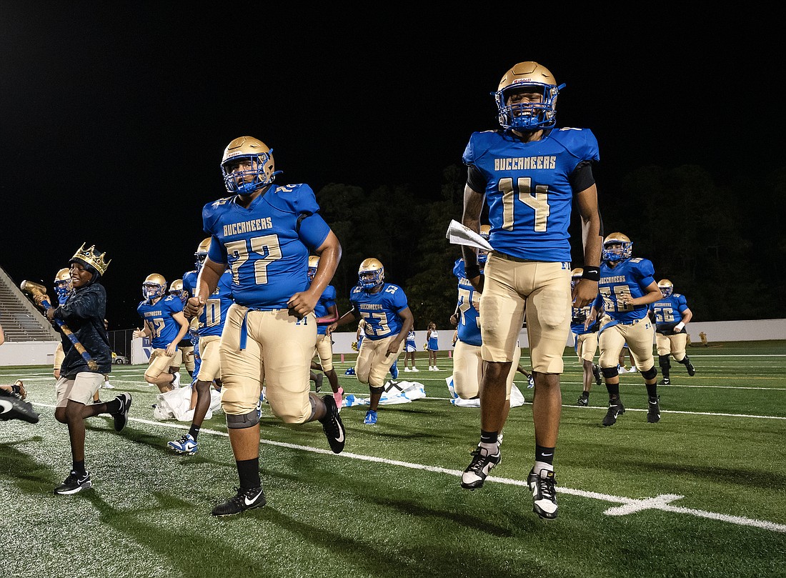 Mainland quarterback Dennis Murray (14) leads his teammates onto the field before the Buccaneers' homecoming game earlier this season. File photo by Michele Meyers