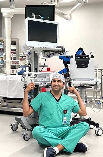 Dr. Ali Tourchy sits by the robot he programs to perform aquablation therapy at AdventHealth Palm Coast Parkway. Courtesy photo