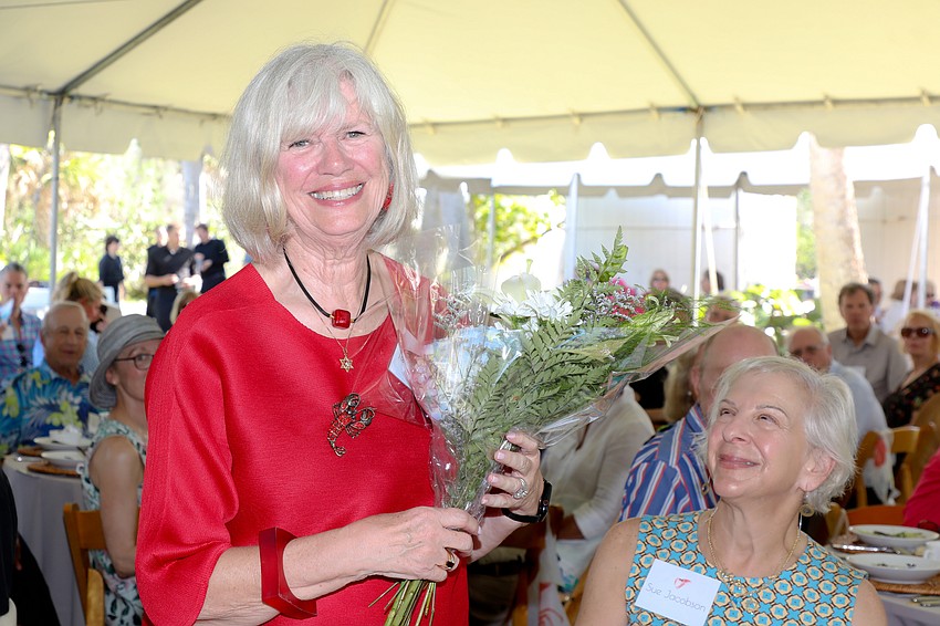 Co-host of today's event is Terry Brackett, who is surprised with a bouquet of flowers as Sue Jacobson looks on.