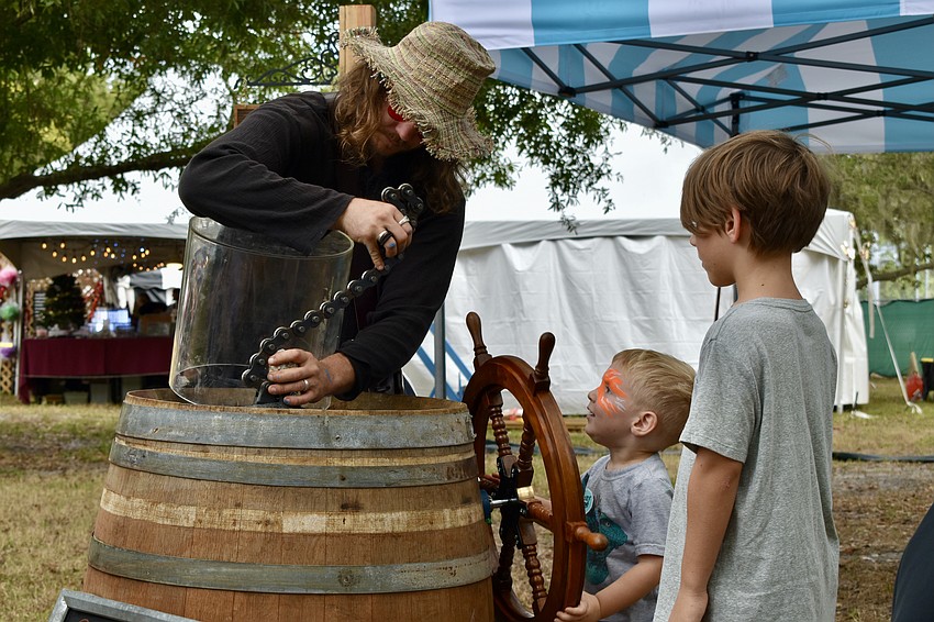 Zach Blankenship helps Asher Fox, 2, and Ryker Fox, 7 to snap a geode in half with a turn of a wheel.