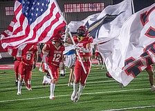 Cardinal Mooney senior Emerson Warthling (24) leads the Cougars onto the field while carrying an American flag.