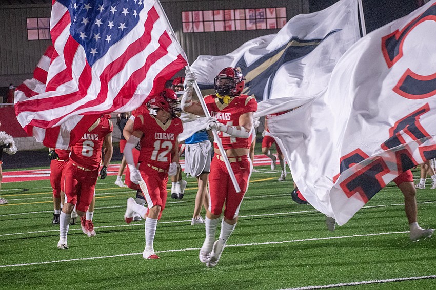 Cardinal Mooney senior Emerson Warthling (24) leads the Cougars onto the field while carrying an American flag.
