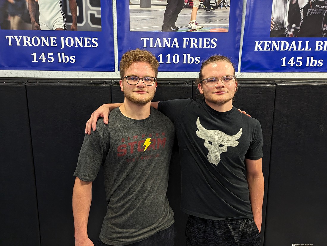 Josh and Caleb Bower pose in front of posters of the three Matanzas High state wrestling champs. Photo by Brent Woronoff