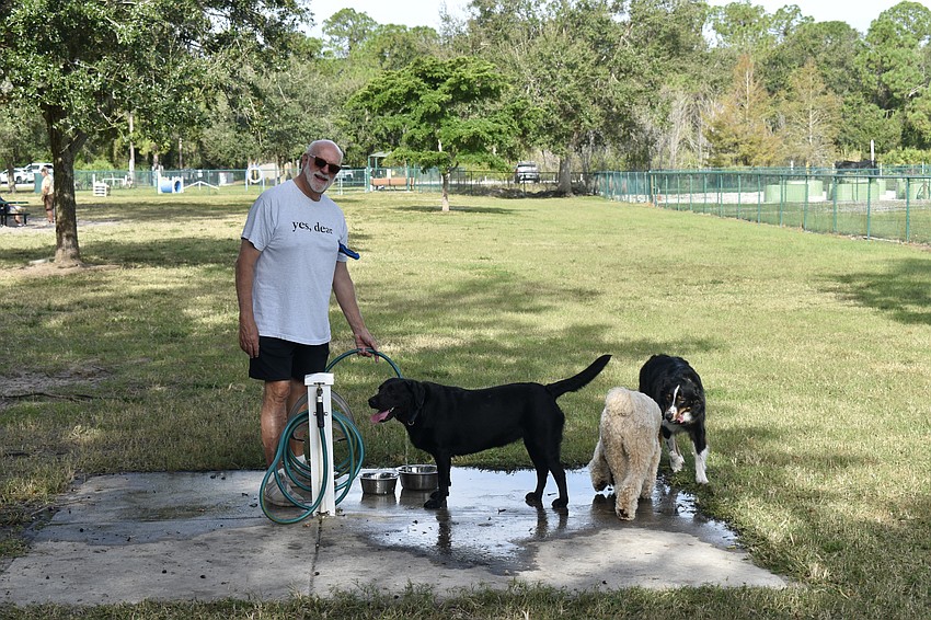 Mark Lee fills up the water bowls. The Greenbrook Adventure Dog Park provides needs such as water and an agility course.