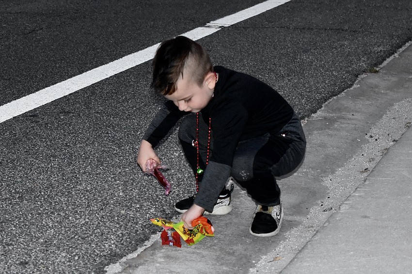 Roland Nyarfadi, 5, picks up candy thrown during the parade.