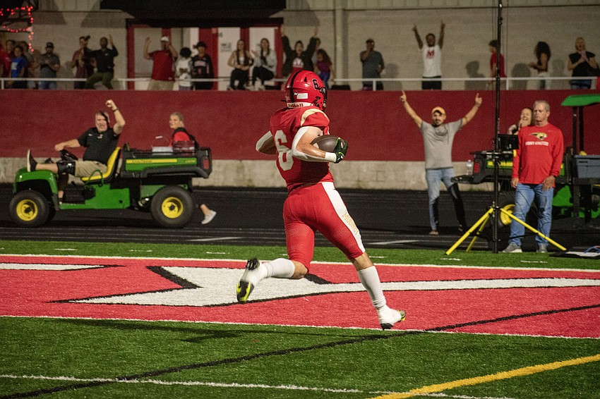 Mooney senior Jacob Brown returns a blocked punt for a touchdown against NFC as Cougars fans celebrate.