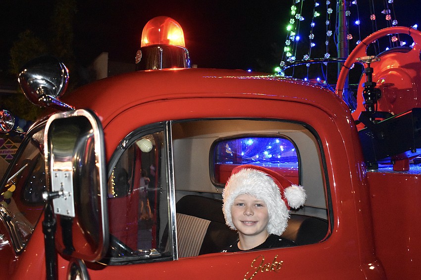 Adam Sperber, 10, takes a turn sitting in the driver's seat of the 1948 Ford fire truck that Warren Middleton, a State Farm real estate agent, used to host Santa Claus.