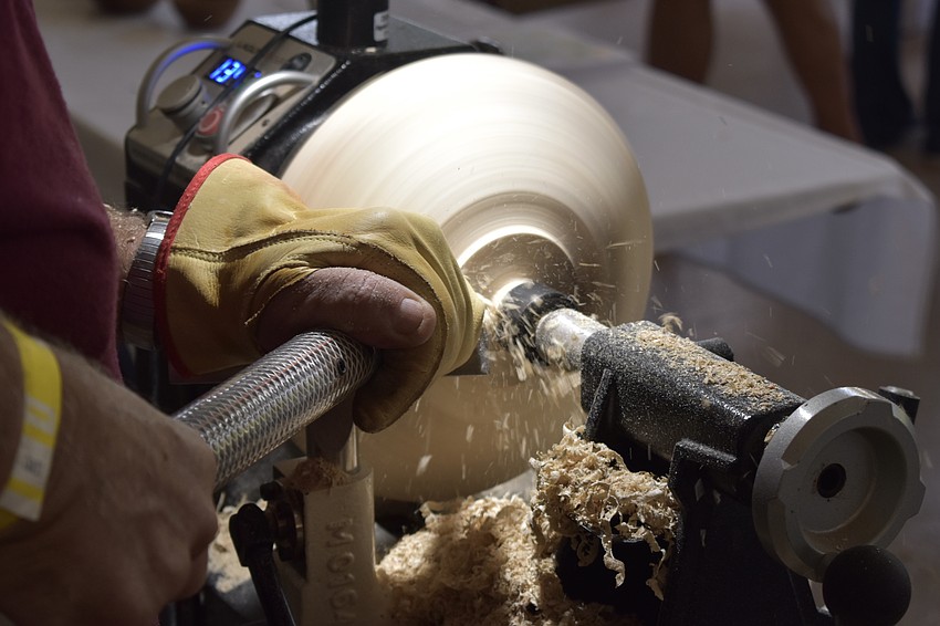 Charley Bell of Sarasota Woodturners carves a wooden bowl.