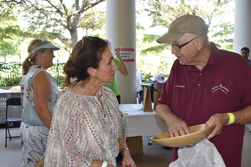 Valerie Hunt discusses a wooden bowl she purchased with Sarasota Woodturners founder Frank Johannesen.