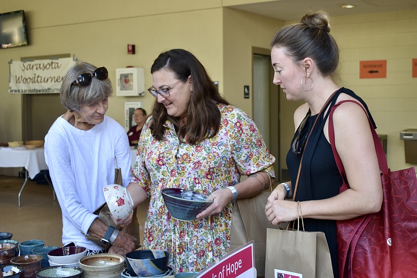 Martha Mumma, Summer Schied and Kirsten Busey browse the ceramic bowls on offer.