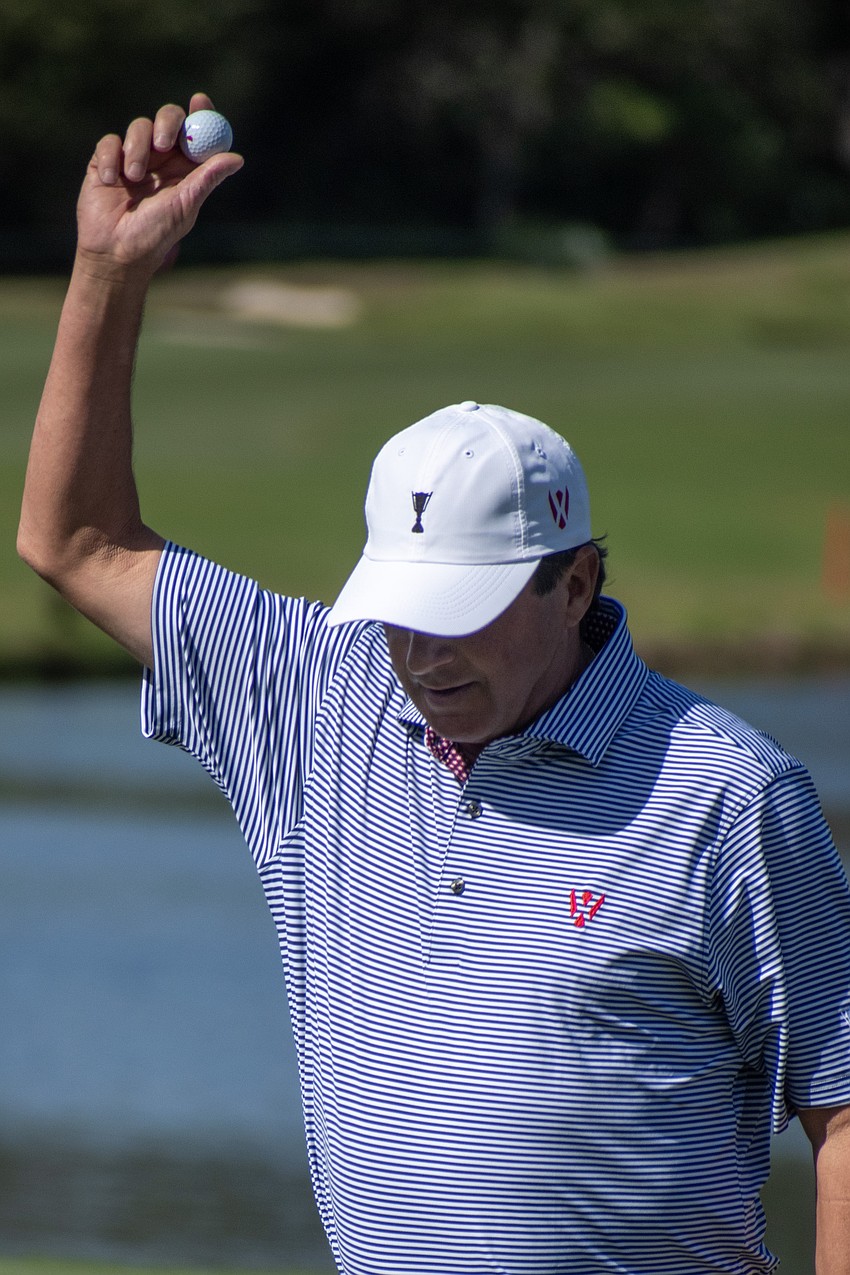 Team USA's Billy Andrade raises his golf ball aloft after sinking a putt on the No. 9 hole at The Concession Golf Club during the morning session of the World Champions Cup. Andrade and teammate Steve Stricker would par the hole.