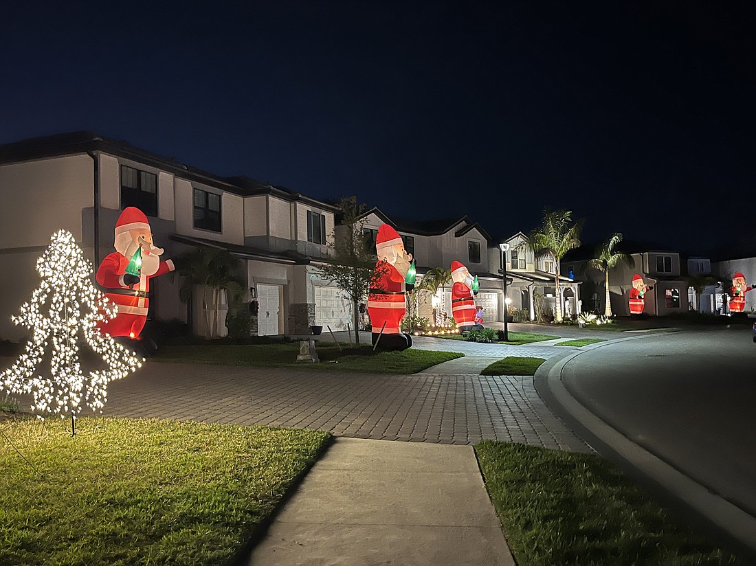 Inflatable Santas line up in front yards of homes on Hidden Oaks Loop.