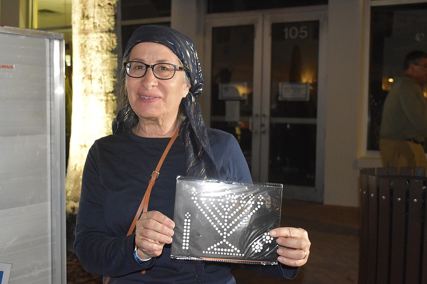 Leba Howitt-Vallone hands out art kits to the kids. The end result looks like a Lite Brite except the lights are stickers.