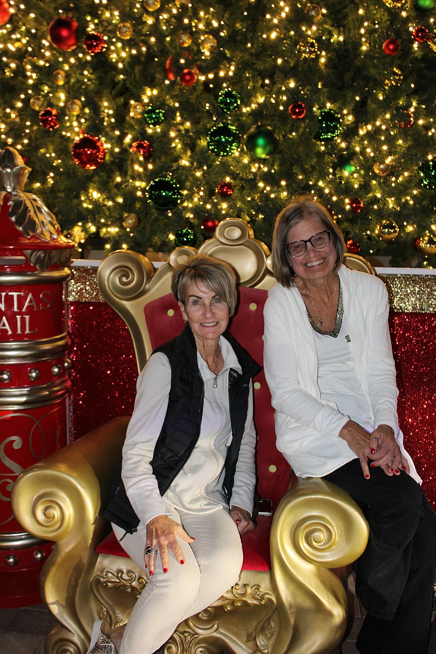 Lakewood Ranch's Kathie Marini and her best friend, Mary Costello of Warren, Ohio try out Santa's chair in front of the big tree at Waterside Place on Friday during the block party.