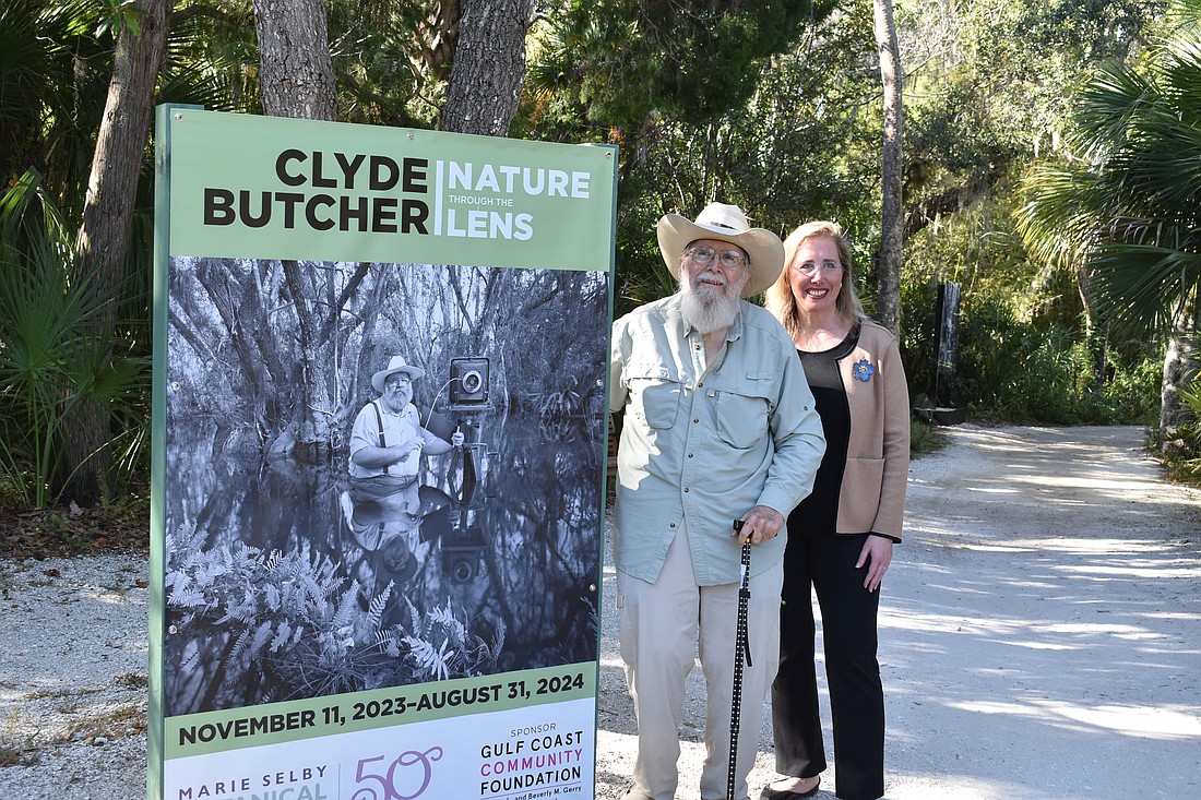 Iconic Florida photographer Clyde Butcher poses with Selby Gardens President and CEO Jennifer Rominiecki at the entrance to the "Nature Through the Lens" exhibition at Spanish Point.