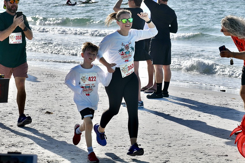 Caleb Sims, 6 and Johanna Sims arrive at the finish line in the 5K.