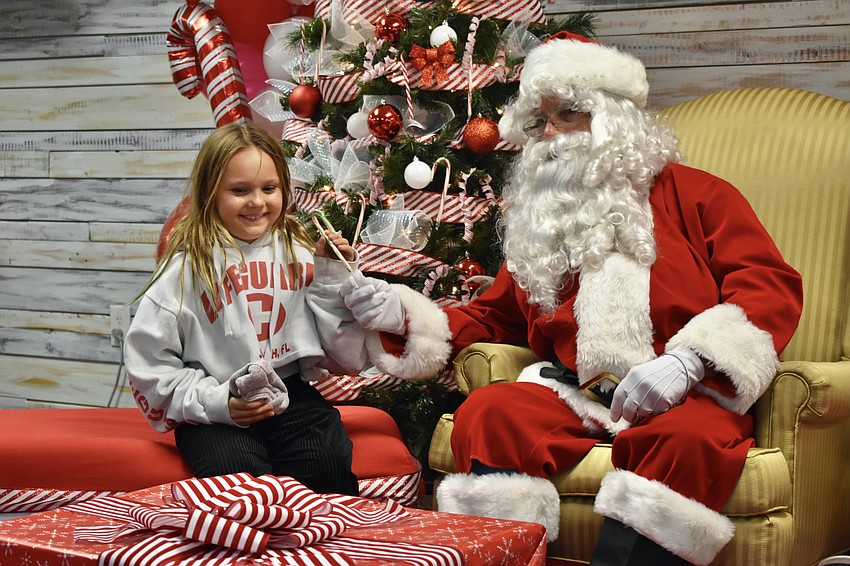 Harper Krull, 8, receives a candy cane from Santa Claus (Jim Maxa).
