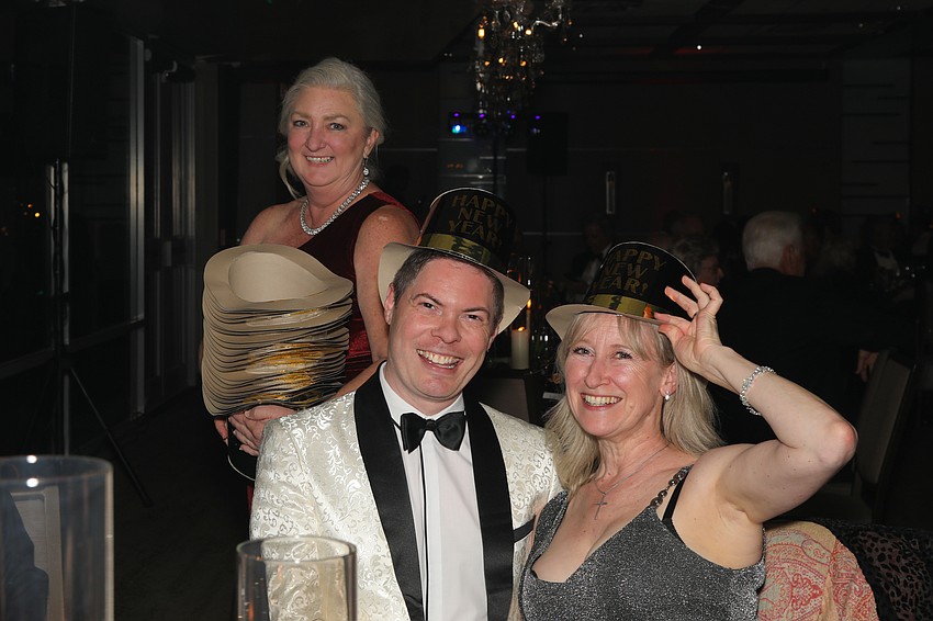  Julie Burton bestows guests Christopher Hird and Elaine Wyatt with New Year's Eve hats.