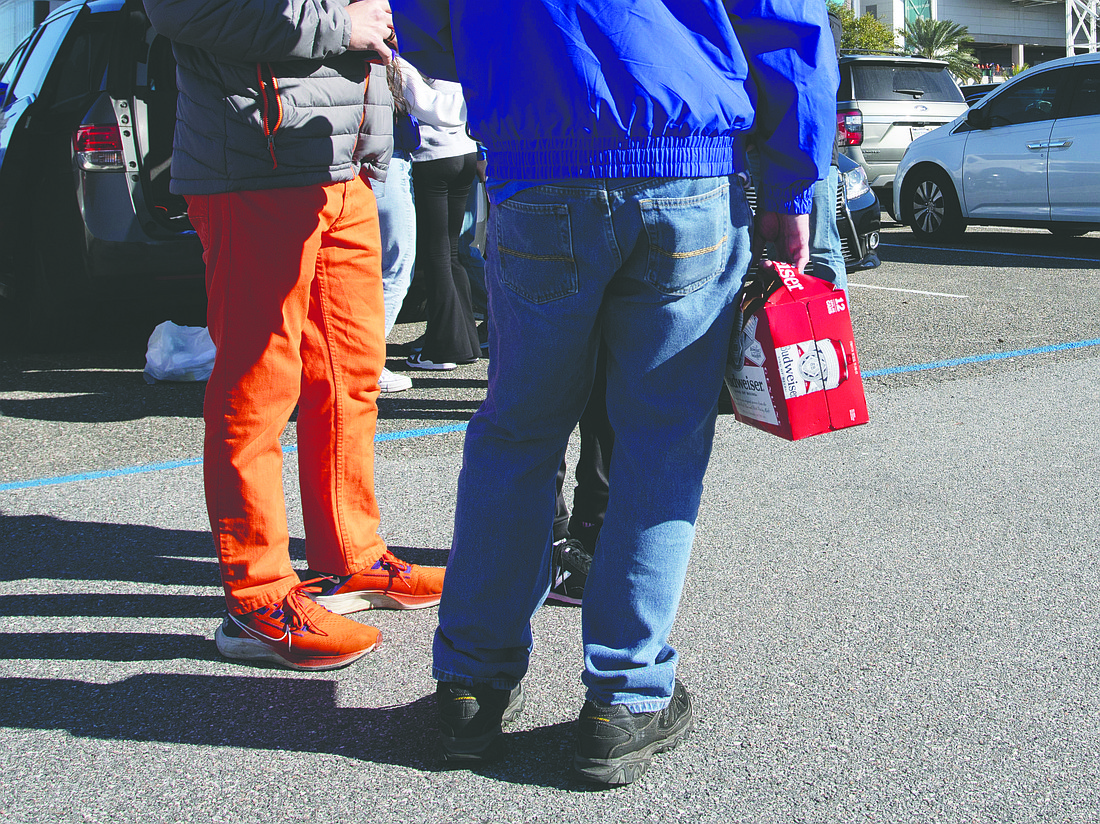 A fan clutches a 12-pack of Budweiser beer in the parking lot at EverBank Stadium before the Clemson University vs. University of Kentucky TaxSlayer Gator Bowl game Dec. 29.