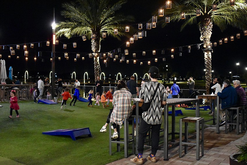 Parents eat and drink their food truck selections while the kids run and play cornhole.