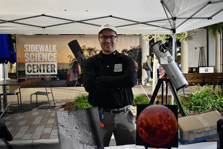 Executive Director Alex Martin mans the booth for the Sidewalk Science Center. The evening is too cloudy to see anything through a telescope.