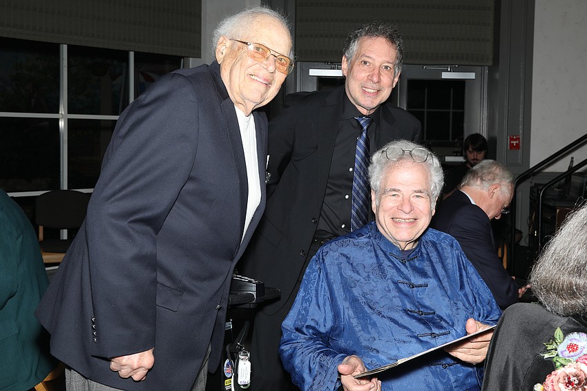 Ted Schvimer and Patrick Romano ask Itzhak Perlman to sign an album cover.
