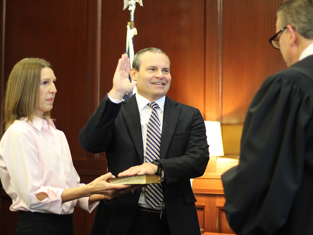 With his wife, Kathleen, holding the Bible, former Assistant State Attorney L.E. Hutton was sworn in as a circuit judge by 4th Circuit Chief Judge Lance Day on Jan. 2.