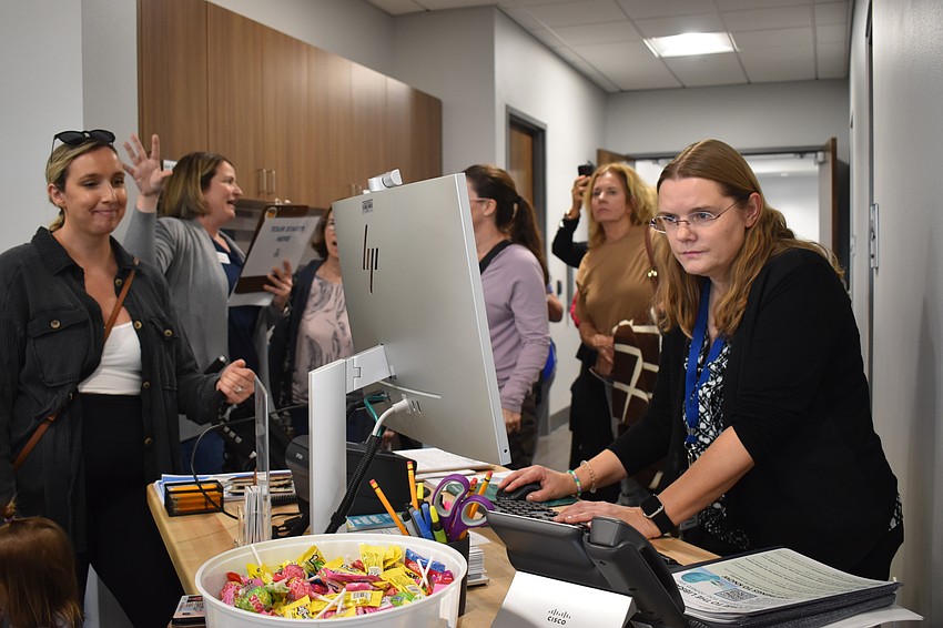 Staff member Nicole Henigschmidt (right) offers help to as many patrons as possible. All six service desks experienced long lines on the first day open.