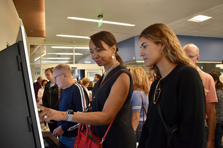 Tammy Robertson tries self-checkout for the first time at the grand opening of the Lakewood Ranch Library. Daughter Skylar Kocourek looks on.