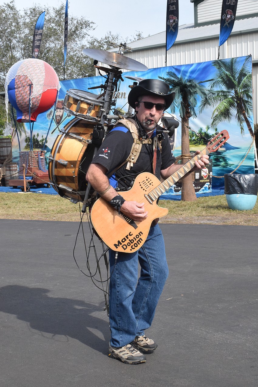 Marc Dobson, the One Man Band, draws a small crowd as he performs.