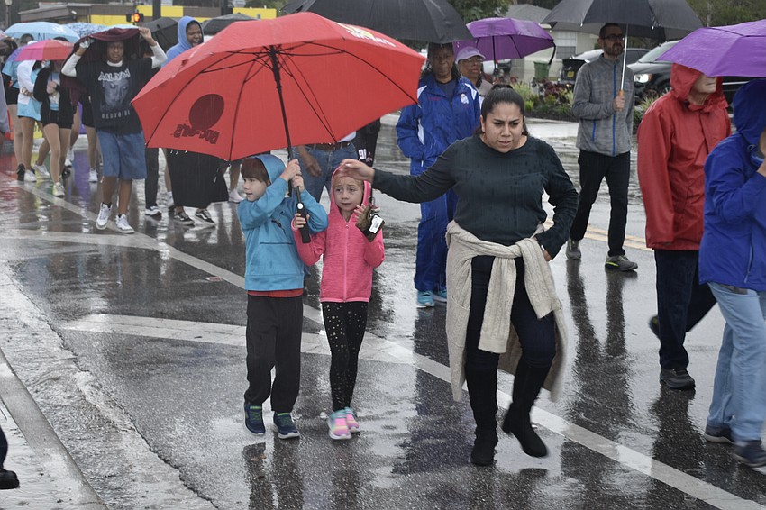 Zachary Anderson, 6, Nevaeh Anderson, 5, and Bianca Flores walk through the rain.