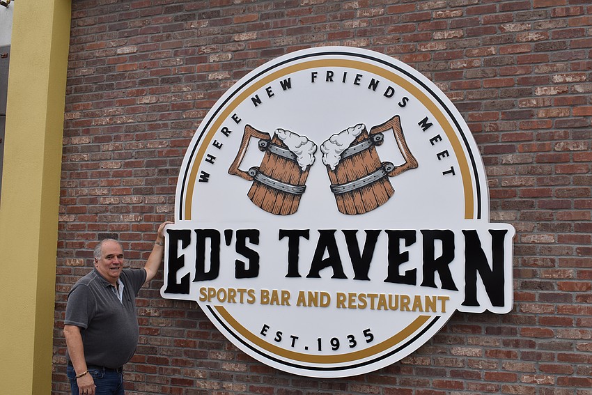 Bob Bender stands next to the huge Ed's Tavern sign that will show passing motorists where they can stop for food and drink.