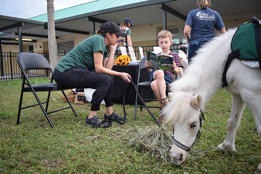 Libby Neily, the director of equine learning with TerraNova, follows along as first grader Jaxon Mackinlay reads 