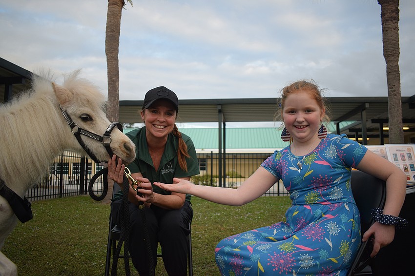 Sugar, a TerraNova mini horse, loves getting attention from Libby Neily, the director of equine learning for TerraNova, and Myakka City Elementary School second grader Aubree Warning.