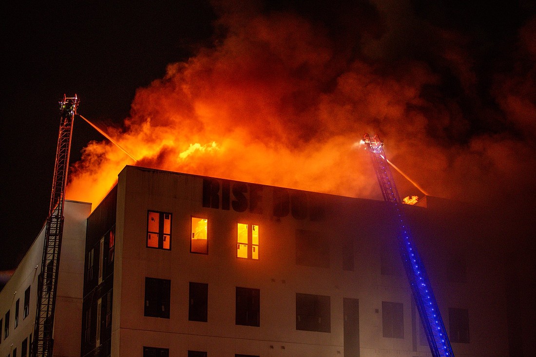 Flames and smoke cast a glow over the top of the Rise Doro apartment building at 960 E. Adams St. in the Downtown Sports and Entertainment District.
