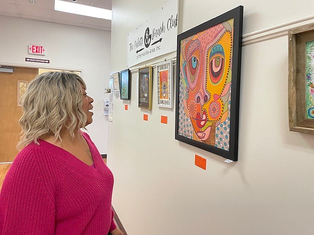 Donna Dungee, a customer service employee at Holly Hill City Hall, looks at art by the Palette & Brush Club of the Halifax. Courtesy photo