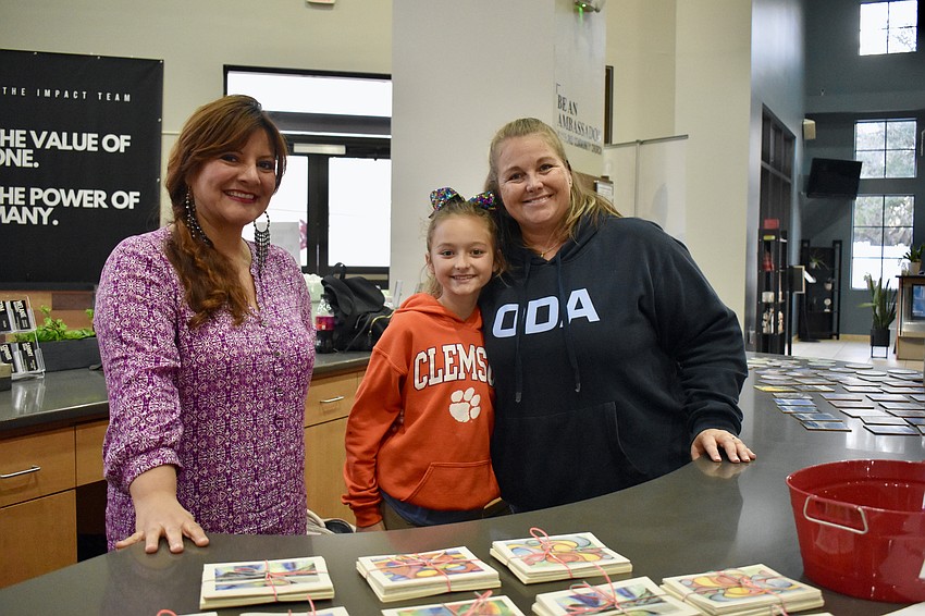 Out-of-Door Academy art teachers Sandra Romero and Leslie Garasie trade student art for donations to Manasota BUDS. Garasic's 9-year-old daughter Regan Garasic helps.