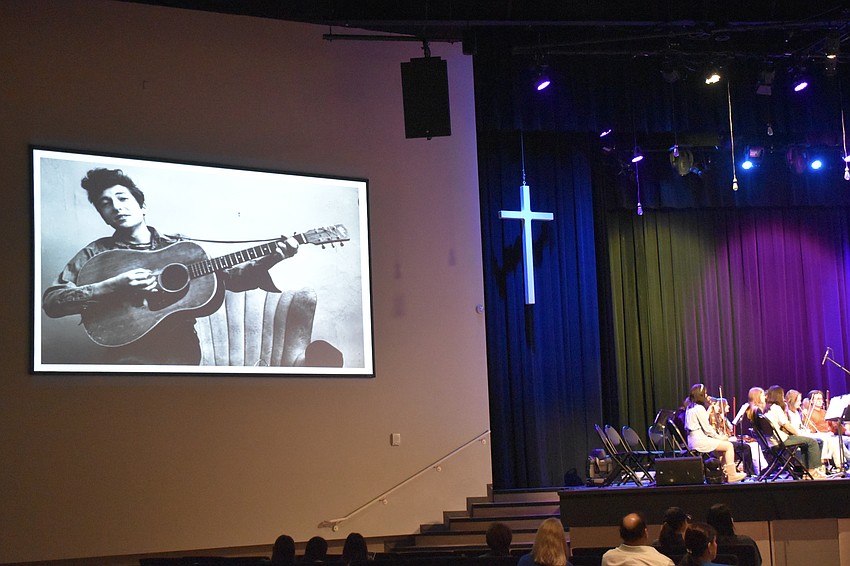 Photos of the artist behind the music are displayed on the wall through each song. Pictured is a young Bob Dylan.